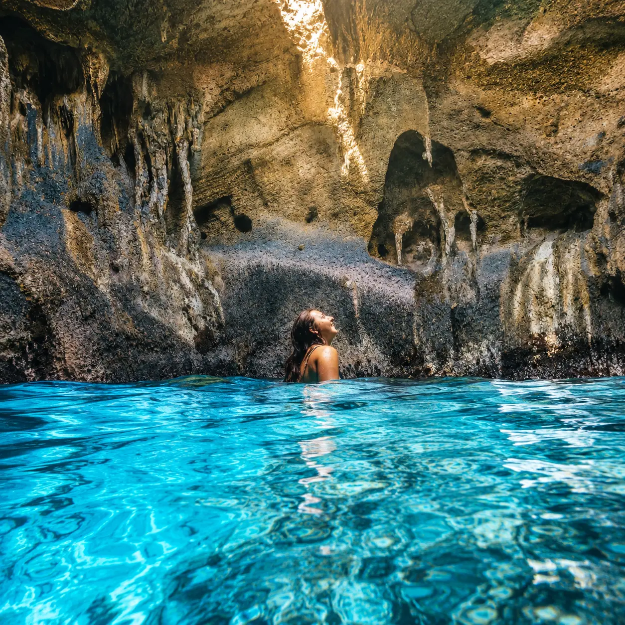 Swimmer inside a sunlit Bahamian sea cave